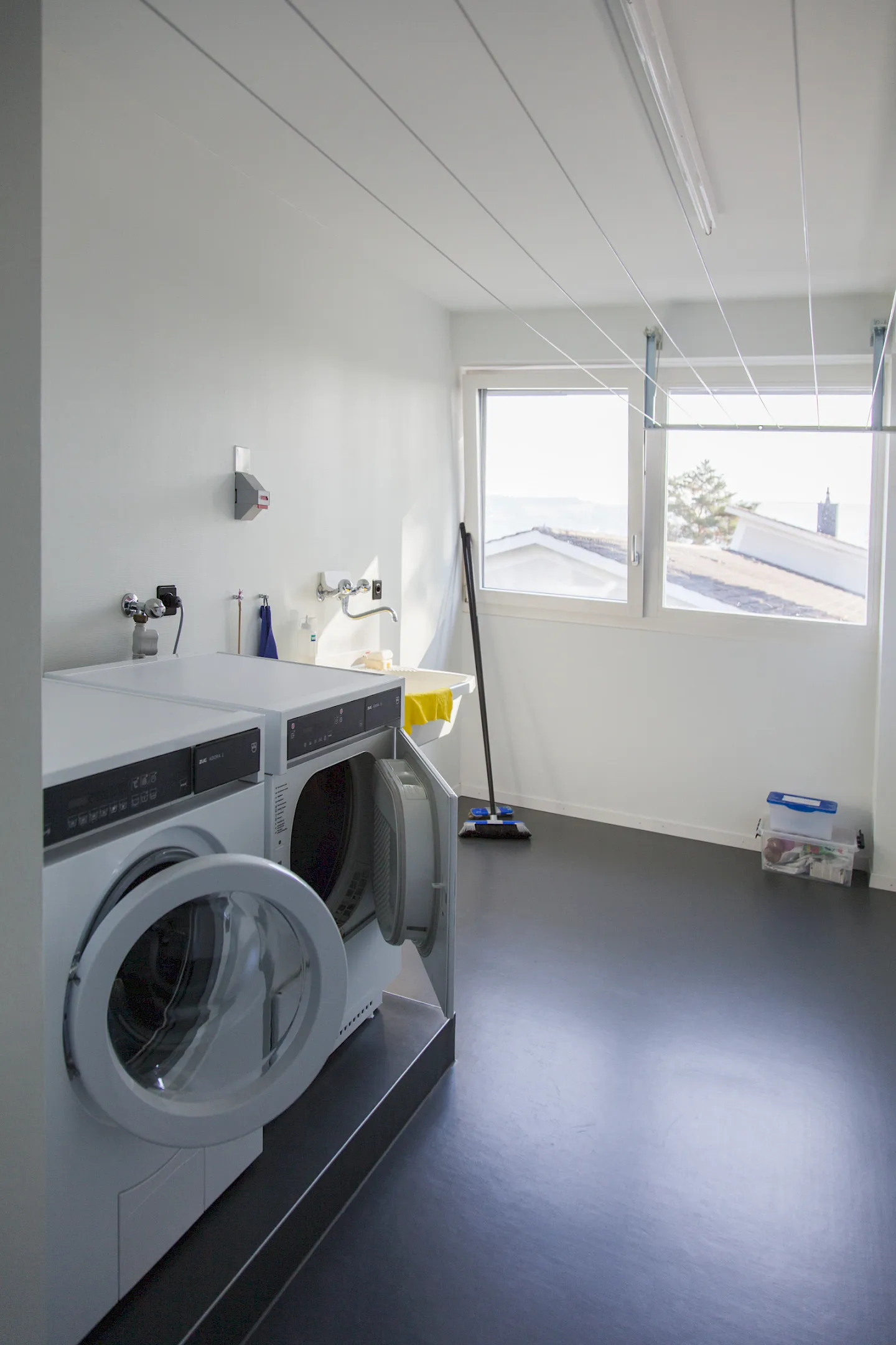 Laundry room with an open dryer, washing machine, and cleaning equipment