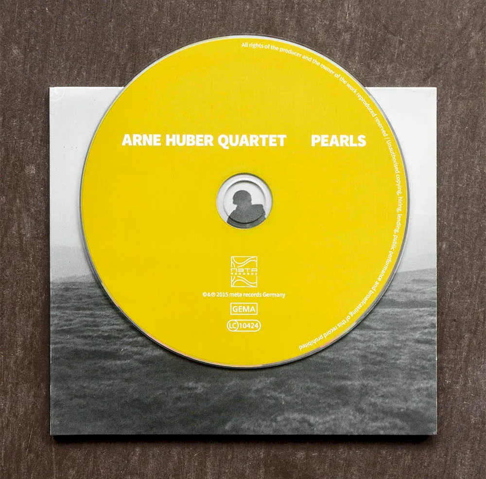 "Pearls" CD with a yellow label; band name and title in black lettering