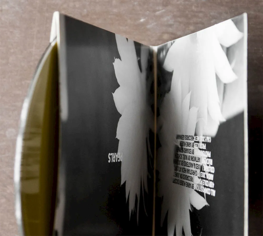 Opened CD booklet for "Pearls" featuring a black-and-white floral motif and credits in mirror writing