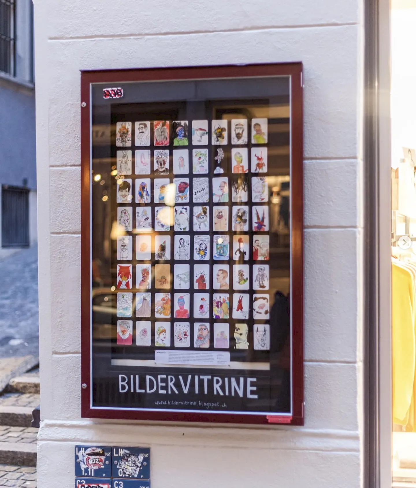 Vitrine an einer Hausfassade mit vielen bemalten Spielkarten unter dem Schriftzug Bildervitrine